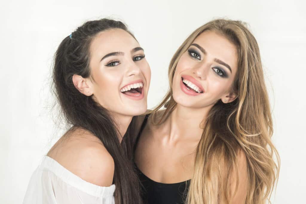 Two beautiful sexy fashion cool happy pretty cheeky hipster girls, blond and brunette.